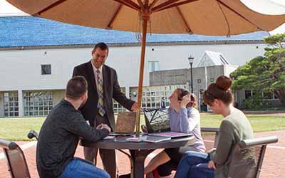 布林·阿森学院教授在户外露台的桌子上与学生交谈